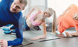 Fitness woman and men in the health club doing a side plank