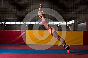 Fitness Woman Performing a Long Jump In Gym