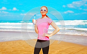 Fitness woman with a plastic bottle water on the beach