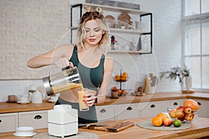 Fitness woman pouring fruits cocktail into glass