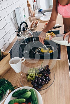 Fitness woman prepare omlette at the kitchen. Mixing milk and eggs into frying pan.