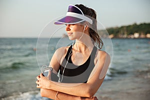 Fitness woman resting on beach listening to music with phone