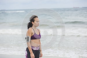 Fitness Woman resting after work out on the beach at cloudy day