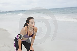 Fitness Woman resting after work out on the beach at cloudy winter day