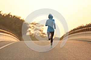 Fitness woman runner athlete running on sunrise road