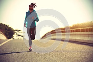 Fitness woman runner running on sunrise road