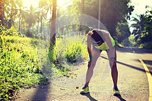 Fitness woman runner take a break at morning tropical forest trail