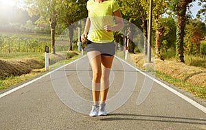 Fitness woman running on asphalt road at sunset