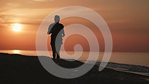 Fitness woman running on morning beach with dramatic sunrise sky. Shot on RED Raven 4k Cinema Camera