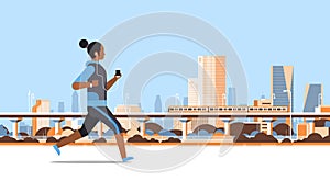 Fitness woman running outdoor african girl listening to music with headphones on smartphone healthy lifestyle concept