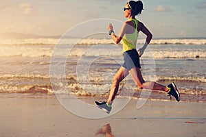 Fitness woman running on sunrise beach