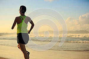 Fitness woman running on sunrise beach