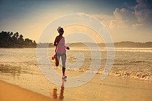 Fitness woman running on sunrise beach