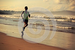 Fitness woman running on sunrise beach