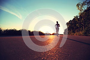 Fitness woman running on sunrise seaside trail