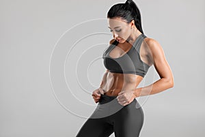 Fitness woman showing abs and flat belly, on gray background. Beautiful athletic girl, shaped abdominal