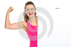 Fitness woman showing biceps and blank billboard