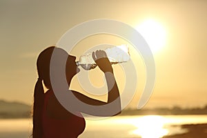 Fitness woman silhouette drinking water from a bottle