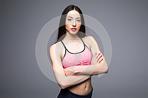 Fitness woman in sports clothes posing on gray background, studio shot