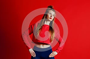 Fitness woman in sportswear standing with hands on hips isolated over red background