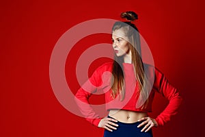 Fitness woman in sportswear standing with hands on hips isolated over red background