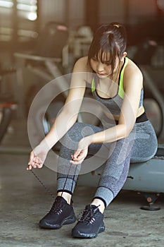 Fitness woman in sportswear tying her shoes for ready to exercise at gym