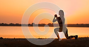 Fitness woman stretching doing lunge stretch exercise. Female athlete training lunges stretches outside in beautiful