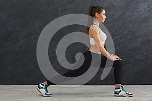 Fitness woman stretching at grey background indoors