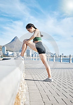 Fitness, woman and stretching legs in Cape Town for running, exercise or cardio workout by the beach. Active female