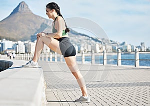 Fitness, woman and stretching legs in Cape Town for running, exercise or cardio workout by the beach. Active female