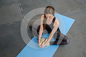 Fitness Woman stretching legs sitting on gym mat. Soirt, and healthy lifestyle.
