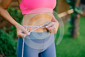 Fitness Woman With Tape Measure Showing Her Waist, close up