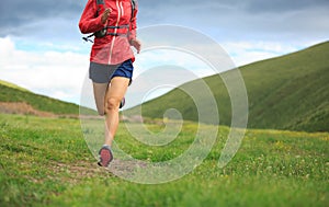 Fitness woman trail runner running on grassland