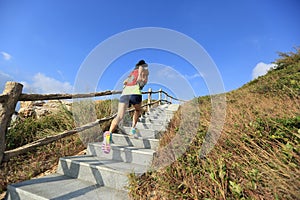 Fitness woman trail runner running up on mountain stairs