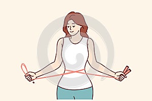 Fitness woman training with jump rope in hands, showing off slender figure and thin waist