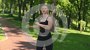 Fitness woman warm up shoulders outdoor. Fit girl stretching in green park