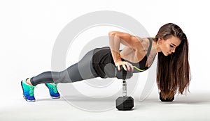 Fitness woman warming up and doing some push ups on a white background. Gorgeous brunette doing push ups on dumbbells.