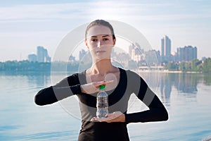 Fitness woman with water bottle at river and city backround