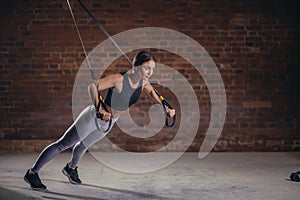 Fitness woman workout on TRX straps in gym. Crossfit style. Training TRX.