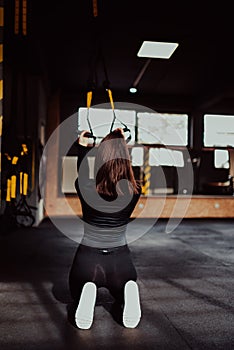 Fitness women work out on the TRX in the gym. Fitness woman workout on CrossFit.