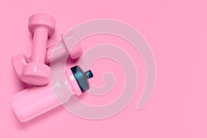 Fitness workout background concept with pink dumbbells and bottle of water. Top view flatlay sport, diet and healthy lifestyle