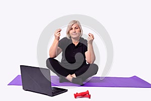 Fitness workout with blonde senior woman working on laptop computer. Power woman multitasking remote work at home