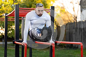 Fitness workout for frontal abs on parallel bars, young man working out