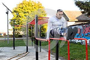 Fitness workout for frontal abs on parallel bars, young man working out