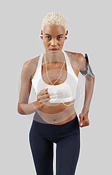 Fitness workout, running woman with earphones of mobile phone on arm band, african latin american female athlete in sportswear,