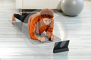 Fitness Workout training. Young healthy fit african girl doing plank exercise on yoga mat on floor at home. Athletic