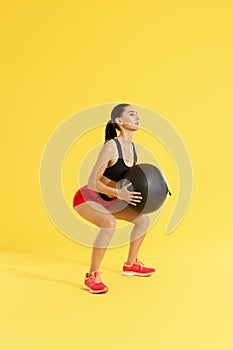 Fitness workout. Woman exercising squats with med ball at studio