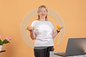 Fitness workout and working on laptop computer - woman multitasking remote work at home indoors lifting dumbbell weights