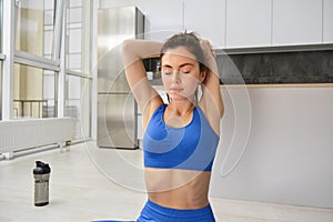 Fitness, yoga and gym at home concept. Young woman doing stretching workout, exercising in living room, fitness training