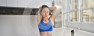 Fitness, yoga and gym at home concept. Young woman doing stretching workout, exercising in living room, fitness training